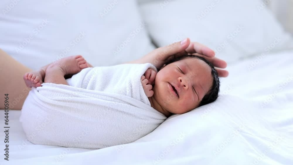 mom's hands of a white-skinned woman gently stroke a newborn African-American dark-skinned baby in a diaper calming him before going to bed, a small child lies on the bed in the bedroom in close-up mom's hands of a white-skinned woman gently stroke a newborn African-American dark-skinned baby in a diaper calming him before going to bed, a small child lies on the bed in the bedroom in close-up
