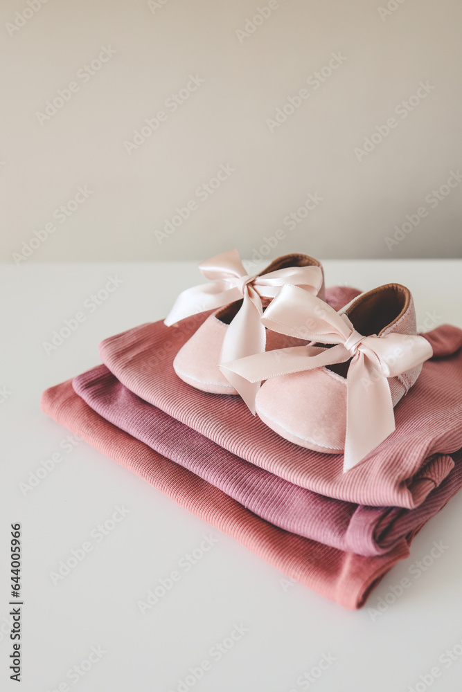 Stack of pink bodysuits and cute slippers with a bow on a white background Stack of pink bodysuits and cute slippers with a bow on a white background