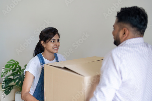 Happy excited beautiful indian young couple move the box into the home at new home. Relocation, moving to new home concept