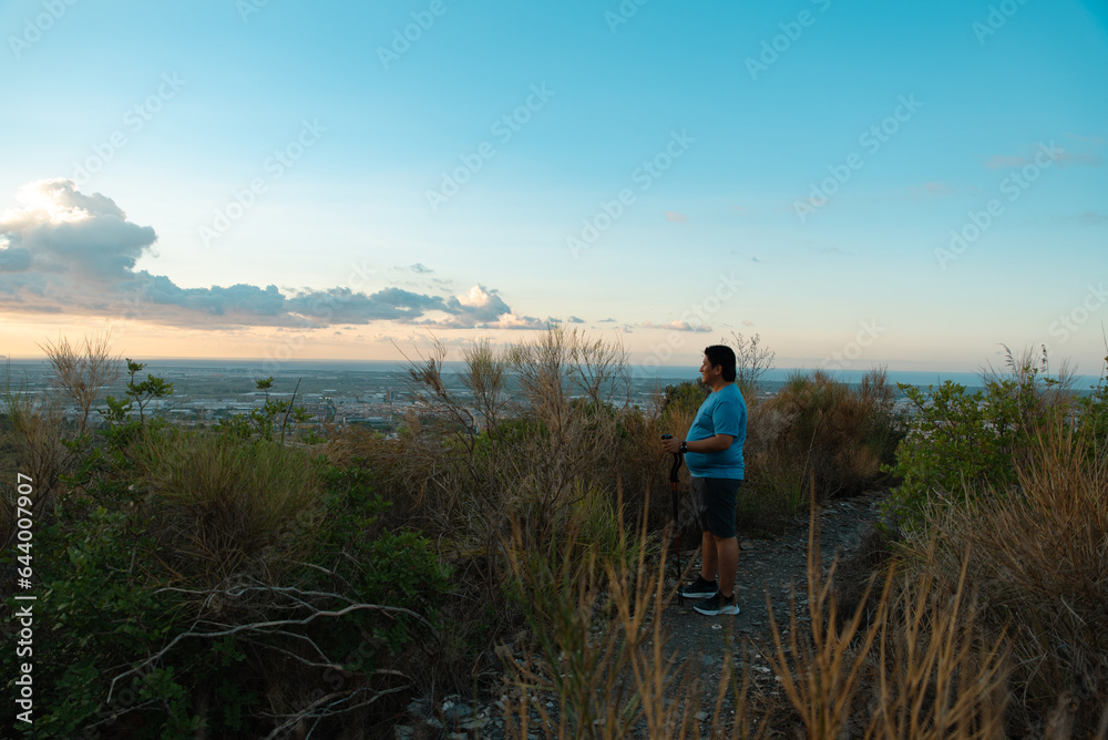 Overweight man stops his training to contemplate the landscape in the morning.