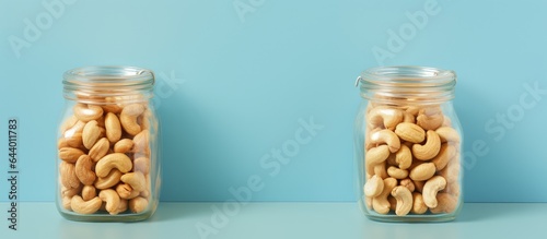 Fried cashews in glass jars with top view on a isolated pastel background Copy space