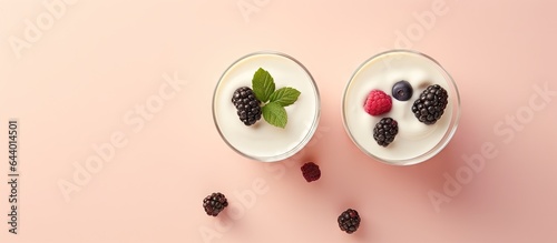 Front view of macro shot of wild berry topped white yogurt in two glasses on a isolated pastel background Copy space