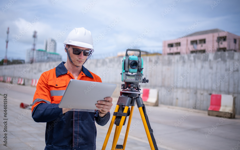 Engineers Surveyor wearing safety uniform ,helmet with equipment theodolite to measurement positioning on the construction site of the road with construct machinery background. Engineers Surveyor wearing safety uniform ,helmet with equipment theodolite to measurement positioning on the construction site of the road with construct machinery background.