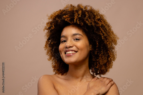 Happy biracial woman with dark curly hair, smiling with hand on shoulder