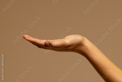 Upturned hand of biracial woman on brown background with copy space