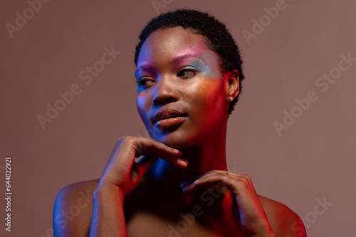 African american woman with short hair and colourful make up touching chin