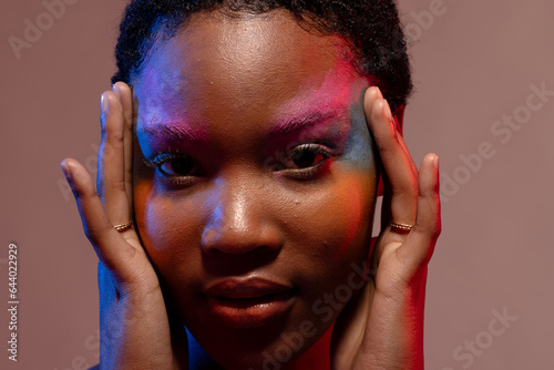 African american woman with short hair and colourful make up touching temples