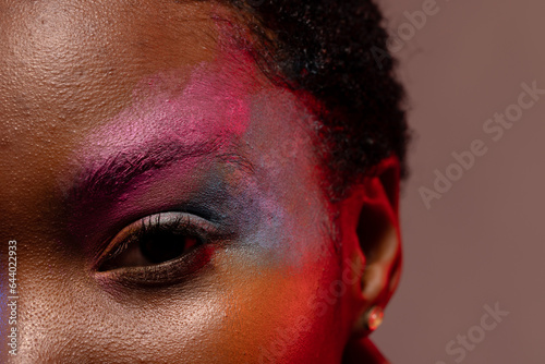 Close up of eye of african american woman with short hair and colourful make up