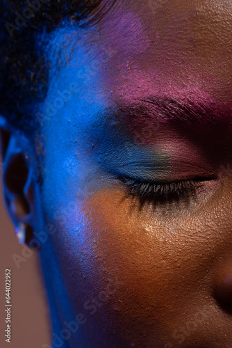 Close up of african american woman with short hair and colourful make up with eye closed