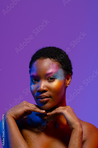 African american woman with short hair, colourful make up and hands under chin, copy space