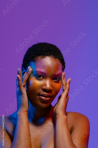 African american woman with short hair and colourful make up touching temples, copy space