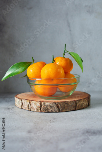 bunch of fresh orange fruits in a glass bowl. mandarin orange on grey and texture background 
