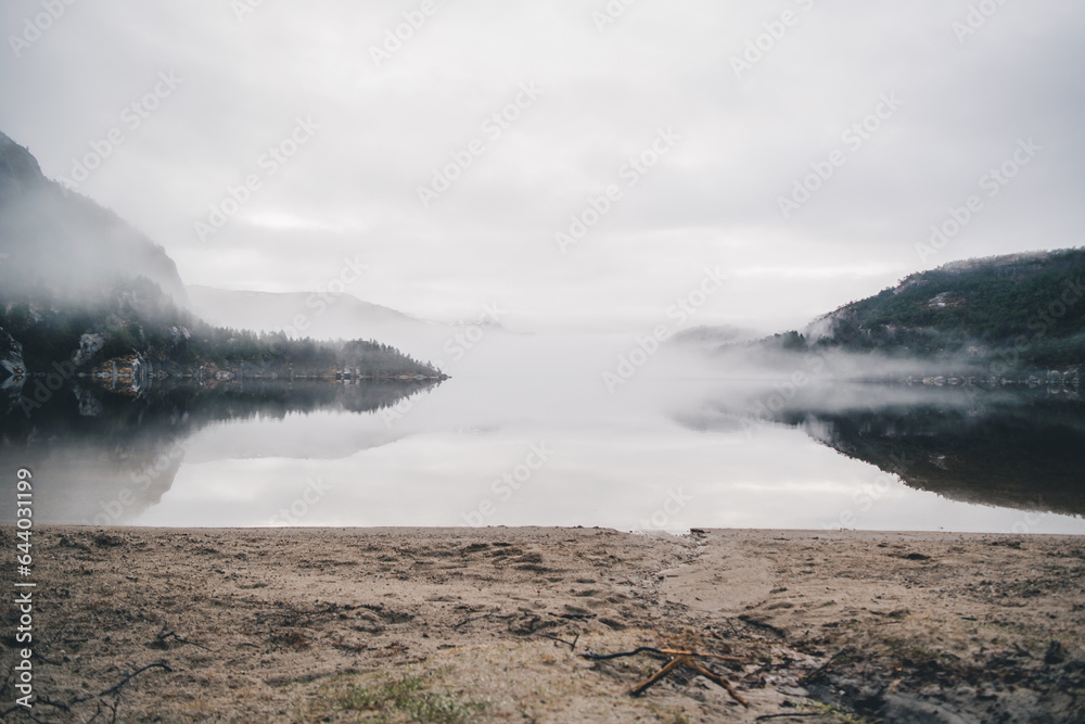 Obraz premium Mountains in Norway. Lake, beach and mountains near Preikestolen. With fog a fairytale picture.