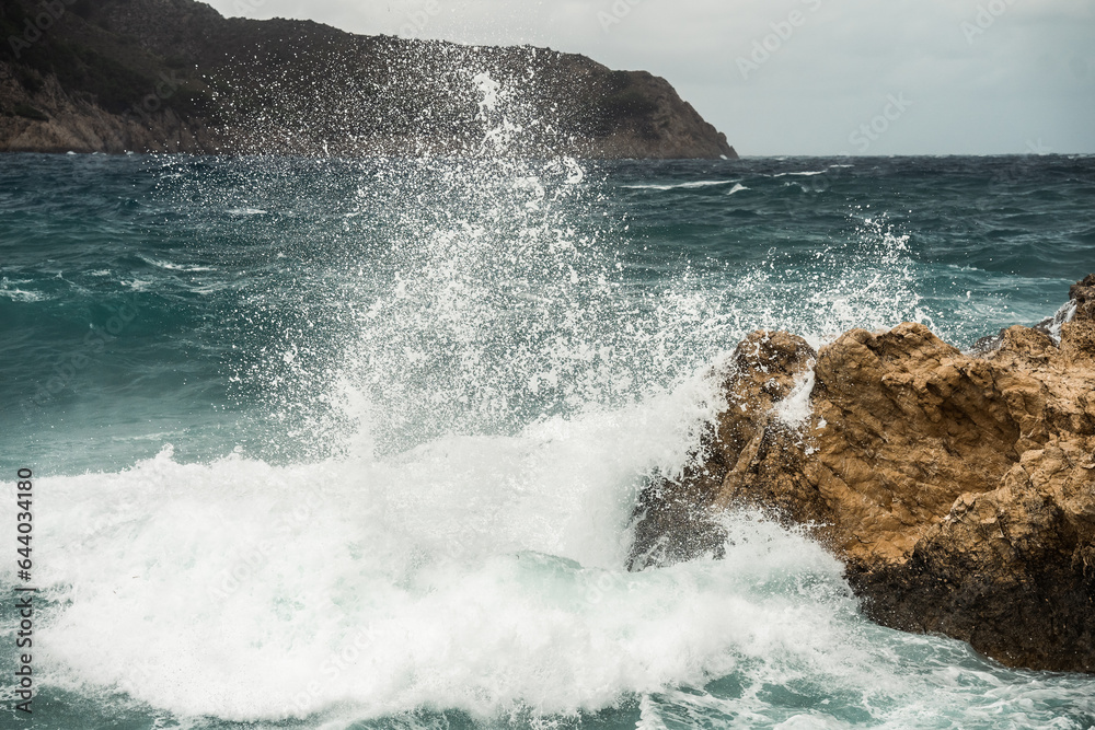 Stürmische Schönheit: Nahaufnahme des aufgewühlten, blauen Ozeans an einem stürmischen Tag in der Bucht von Cala Agulla, Cala Ratjada, Mallorca Stürmische Schönheit: Nahaufnahme des aufgewühlten, blauen Ozeans an einem stürmischen Tag in der Bucht von Cala Agulla, Cala Ratjada, Mallorca