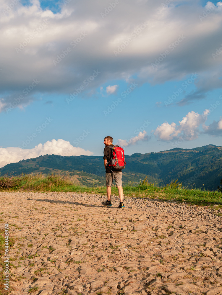 Millennial man hiking with backpack Carpathian Mountains road climbing peak scenic view. Travel Lifestyle wanderlust adventure vacations Bearded guy walking outdoor alone into the wild Ukraine, Europe