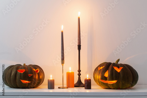 black halloween pumpkin with burning candles in white interior photo