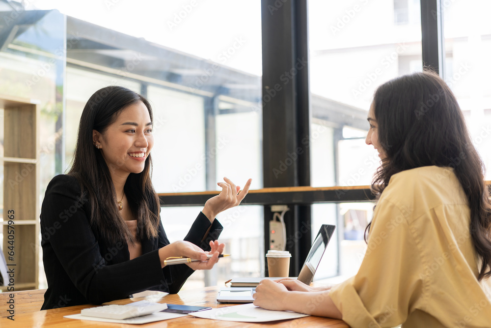 Two female Asian accountants discuss financial management planning. Analysis of new startup project ideas Two female Asian accountants discuss financial management planning. Analysis of new startup project ideas