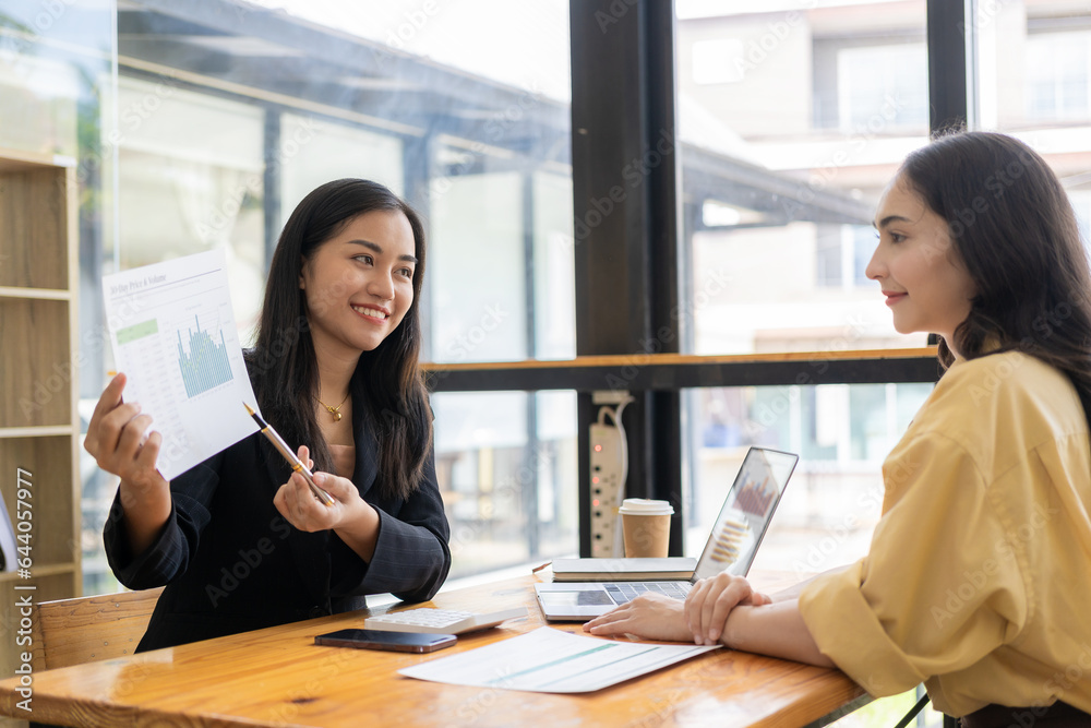 Two female Asian accountants discuss financial management planning. Analysis of new startup project ideas Two female Asian accountants discuss financial management planning. Analysis of new startup project ideas