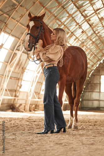 Full height photo. Beautiful young woman is with horse indoors © standret