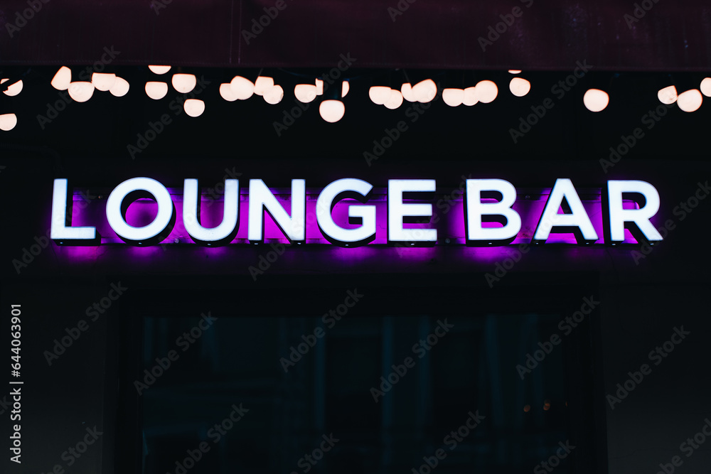 Neon sign on a black background, the inscription Lounge bar with purple light