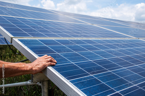 The hand on Solar panel On a solar farm Natural energy is a clean energy and has little impact on the community.