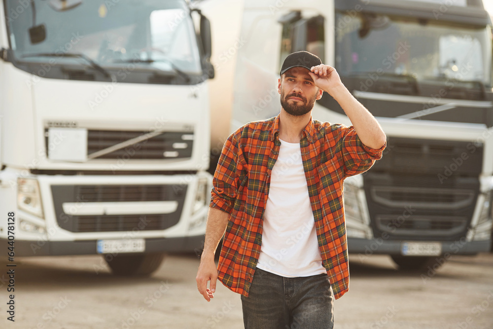 Fototapeta premium Bright sunny day. Young truck driver in casual clothes