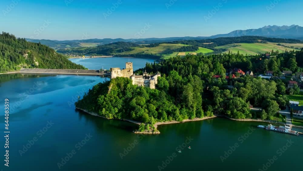 Poland. Medieval castle in Niedzica in sunset light. Artificial Czorsztyn lake on Dunajec river, stand up paddlers, dam and hydro power station. Tatra Mountains in the background. Aerial panning video Poland. Medieval castle in Niedzica in sunset light. Artificial Czorsztyn lake on Dunajec river, stand up paddlers, dam and hydro power station. Tatra Mountains in the background. Aerial panning video