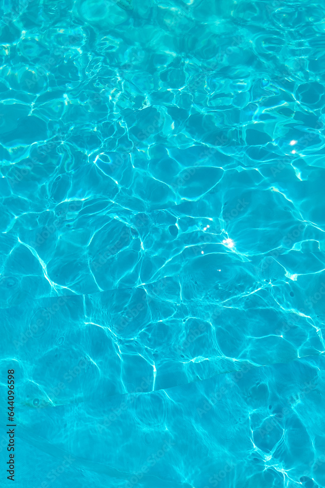 Azure transparent texture of water in a blue pool with splashes from the sun