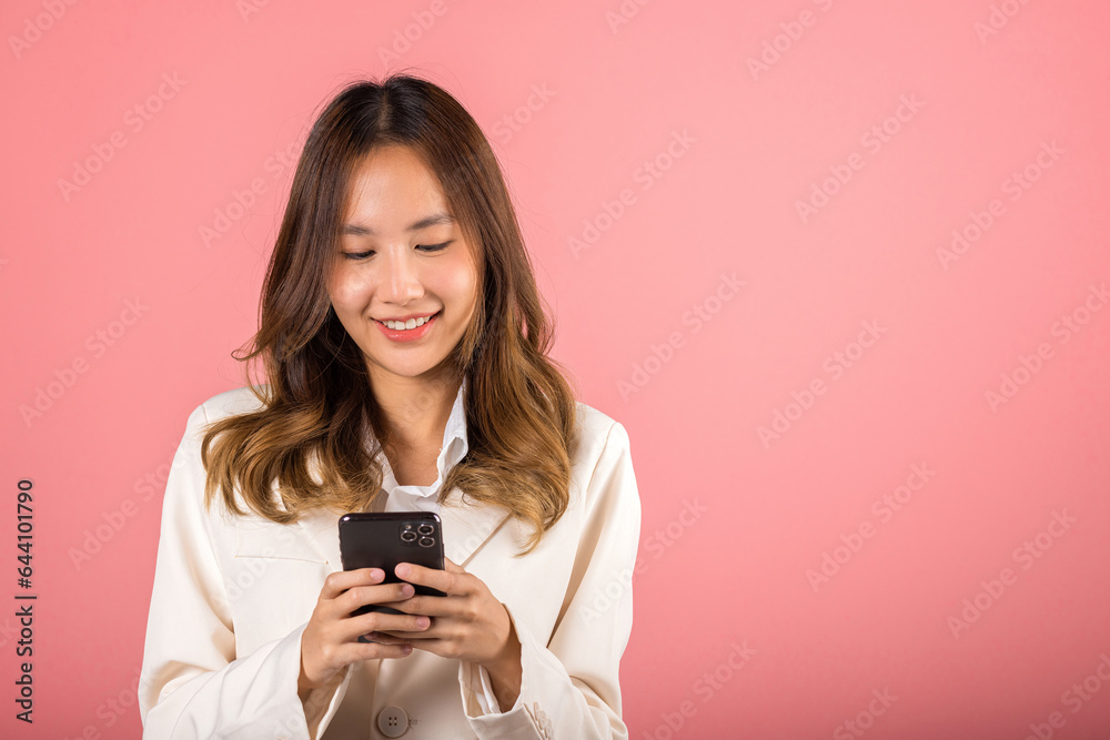 Happy Asian portrait beautiful cute young woman teen smiling excited hold smart mobile phone studio shot isolated on pink background, Female surprised and sms chatting internet online on smartphone Happy Asian portrait beautiful cute young woman teen smiling excited hold smart mobile phone studio shot isolated on pink background, Female surprised and sms chatting internet online on smartphone