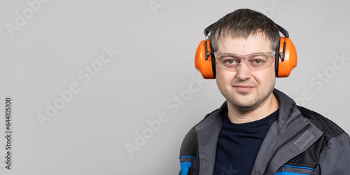 A man in earmuffs, glasses and overalls on a white background. photo