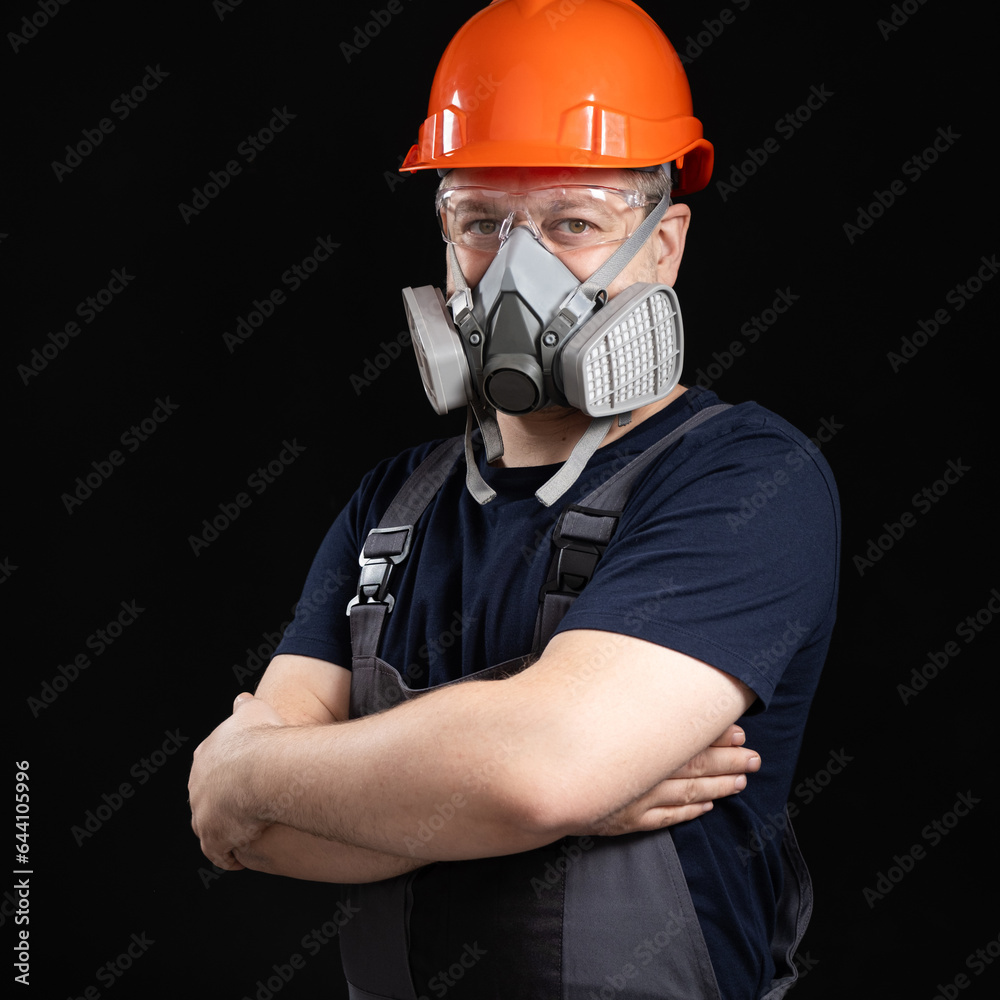 A man wearing a helmet, respirator and goggles on a black background