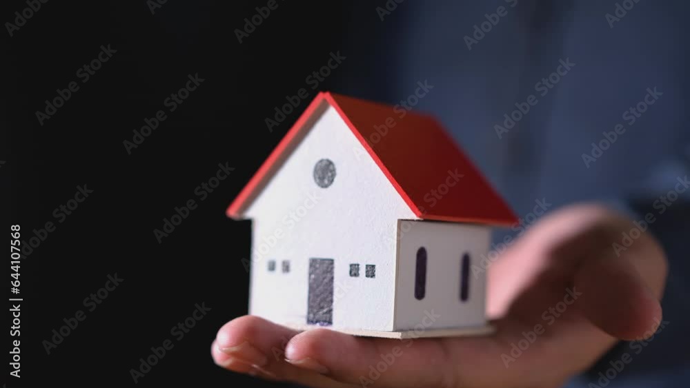 man's hand is holding a house model in his hand. man's hand is holding a house model in his hand.