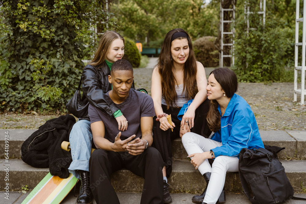 Young friends talking while sitting on steps Young friends talking while sitting on steps