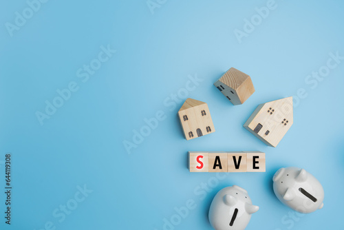 Top view, Flat lay SAVE on wood of cube with 2 piggy banks, and little wood house on blue background with copy space. Financial, Accounting, banking, investment, saving money concept.