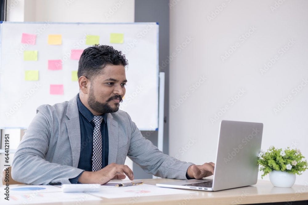 Young handsome happy man working in office on laptop and smiling Young handsome happy man working in office on laptop and smiling