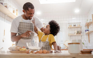 Portrait of African American dad little son having fun in kitchen home, baking pastry in modern kitchen together, kneading Dough prepare cookie pizza. Love fun make homemade food hobby or leisure time