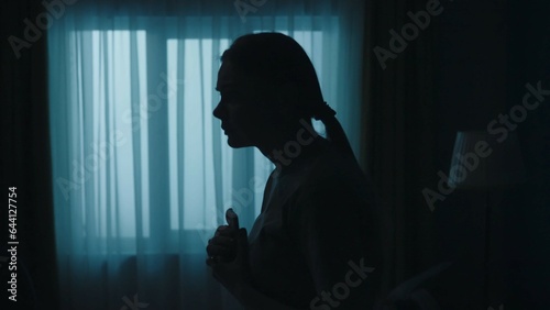 Bild auf Leinwand Young shocked woman in the dark room, holding smartphone, looking scared