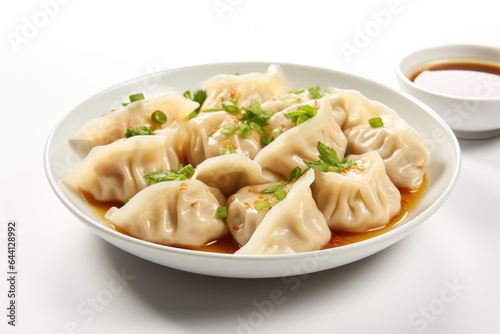 A plate of wonton dumplings and a bowl of sauce. Digital image.