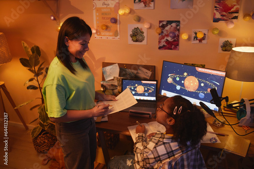 Side view portrait of young African American woman helping daughter with homework in evening in cozy room, copy space