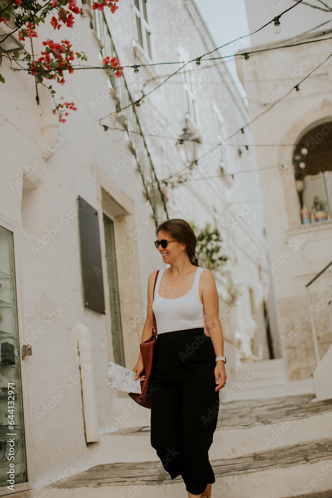 Female tourist with paper city map on narrow streets of Ostuni, Italy Female tourist with paper city map on narrow streets of Ostuni, Italy