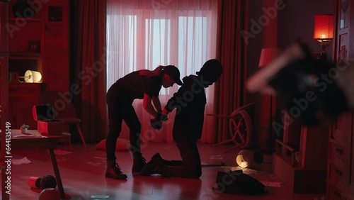 Fotografie The arrest of the robber in a dark apartment, lit with red light