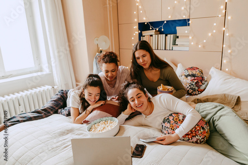 Cheerful multiracial friends watching movie together on laptop at home