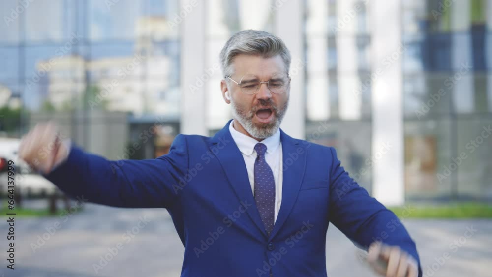 Lucky Caucasian Handsome Businessman Wearing Glasses and Earphones is Celebrating His Victorious Achievement by Dancing in the Street, Outside - Way to Success Concept. Success, New Life
