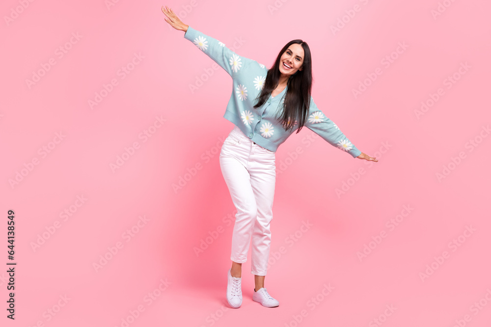Full length photo of cute carefree woman dressed blue cardigan arms sides having fun isolated pink color background