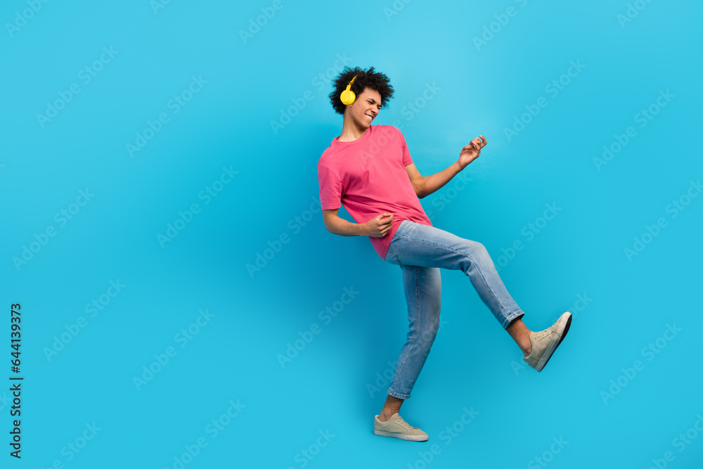 Full length photo of nice young guy yellow headphones play guitar instrument dressed stylish pink garment isolated on blue color background