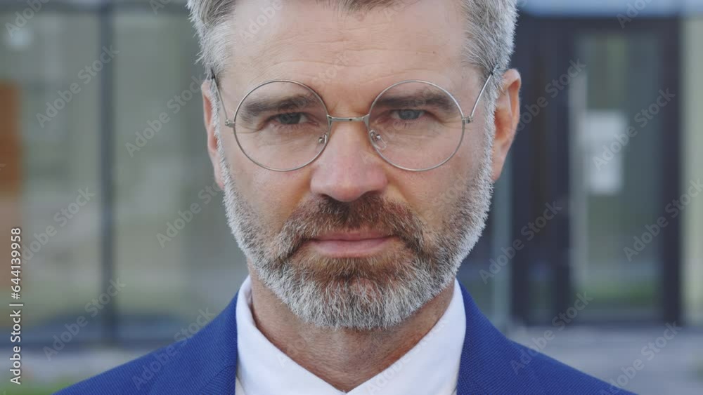 Portrait Of Focused Handsome Male Looking In the Camera Wearing Glasses. Close up Confident Manager Posing in Earphones. Matured Business Man Standing. Bearded Guy Wearing Costume Outdoors Portrait Of Focused Handsome Male Looking In the Camera Wearing Glasses. Close up Confident Manager Posing in Earphones. Matured Business Man Standing. Bearded Guy Wearing Costume Outdoors