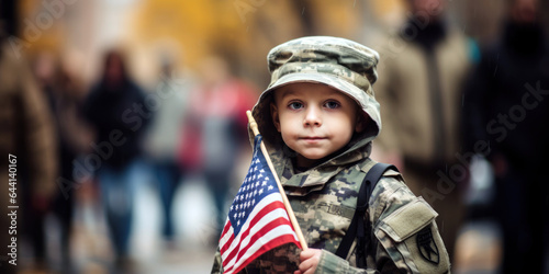 child holding US Flag, stands beside a parade route, in military uniform
