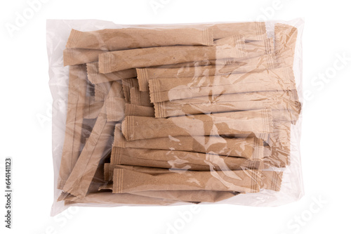 heap of sugar sticks in transparent plastic bag, sugar in paper kraft packaging, mock up for design isolated on white background with clipping path