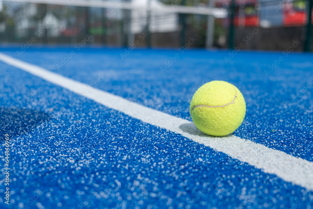 selective focus, a paddle tennis ball over the line of a blue paddle tennis court