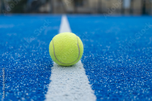 selective focus, a yellow ball over the line of a blue paddle tennis court © Vic